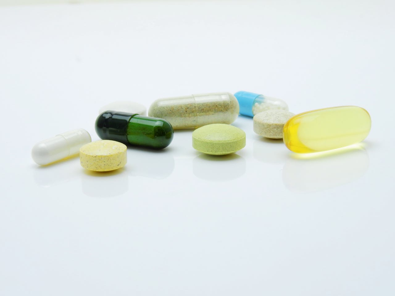 creative-02 Close-up of various pills and capsules arranged on a white surface, representing healthcare and medicine.